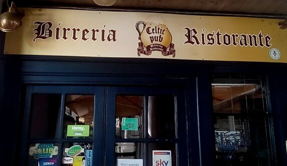 Gruppo di amici seduti a un tavolo di pub con birre durante una partita di rugby